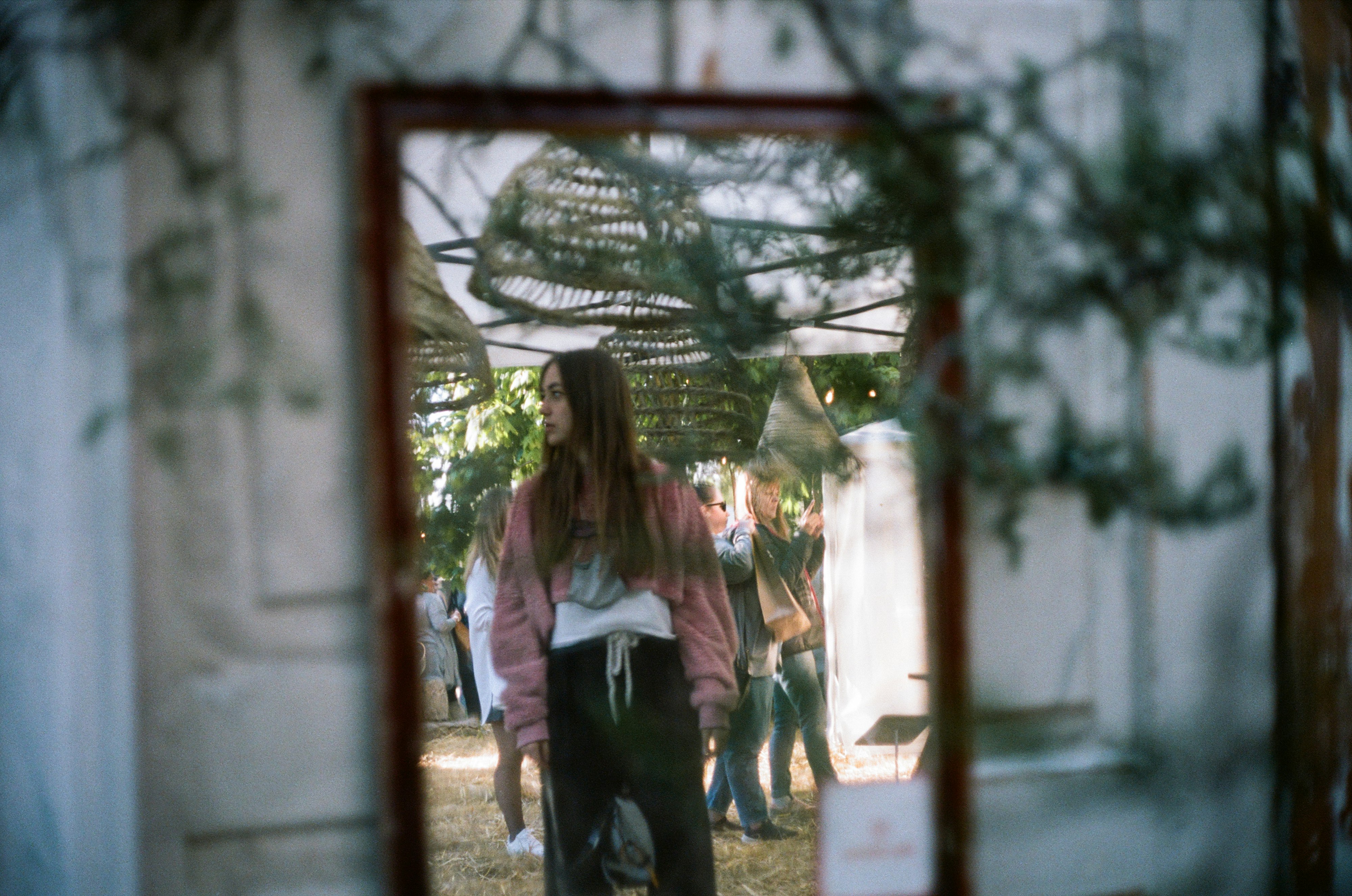 woman in white long sleeve shirt and black pants standing near green plants during daytime